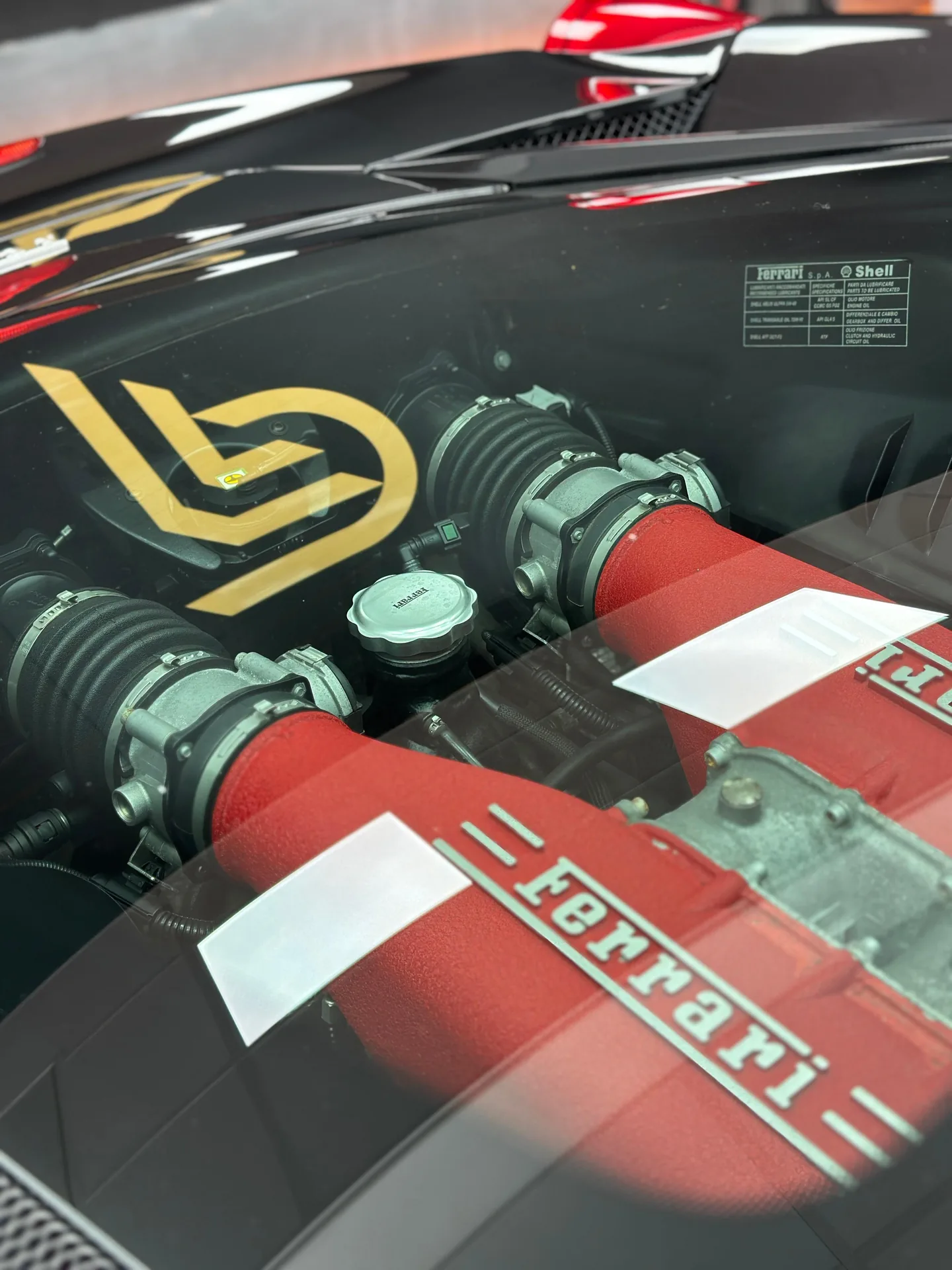 Ferrari V8 engine seen through the rear engine cover glass, with the Pure PPF logo reflected