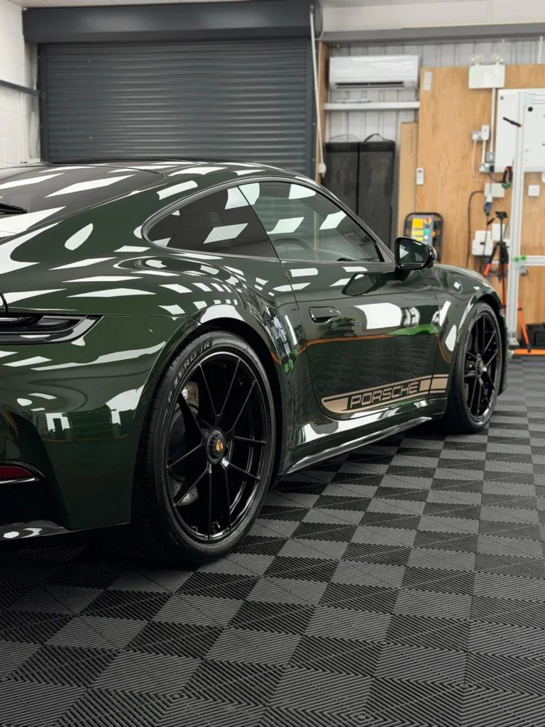 Green Porsche 911 in the Pure PPF studio, rear three-quarter view